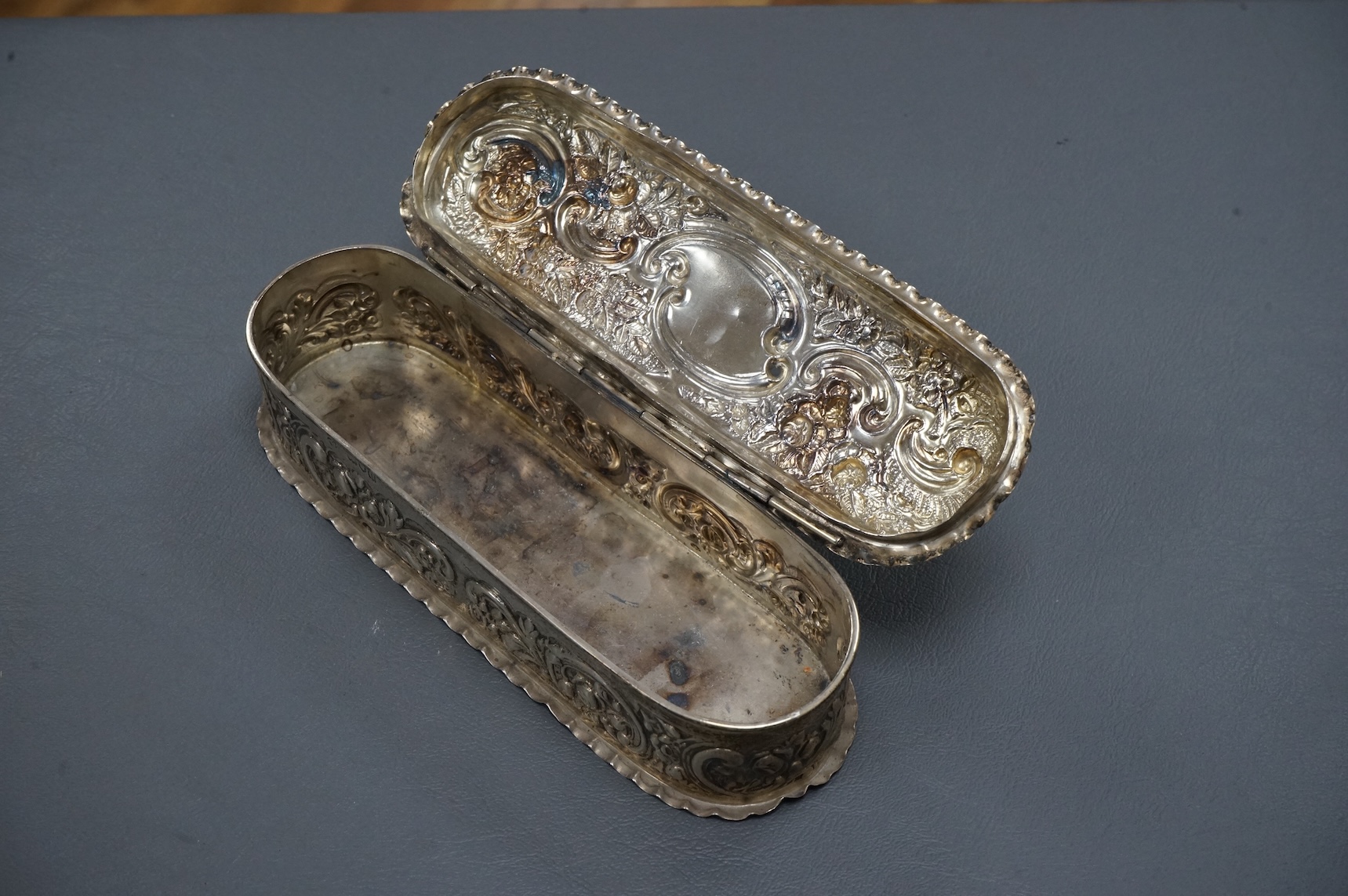 An early 20th century repousse silver dressing table tray by William Comyns & Sons Ltd, London, 1901, 25.1cm, together with a matching oval trinket box, London, 1900, 16.6oz (a.f.).